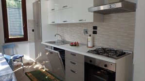 Una cocina moderna con armarios blancos, un lavamanos de acero inoxidable, una estufa a gas y un lavavajillas.