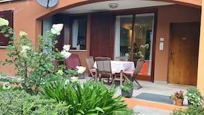 Une terrasse avec une table et des chaises, une porte et une fenĂȘtre avec des rideaux.