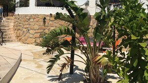 A white building with a stone base, a tiled patio, and a satellite dish. - Beautiful Villa in El Campello with Private Pool and a Step from the Sea (El Campello)