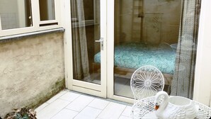 A room with a bed, a white swan-shaped mug, and a decorative chair.