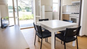 A modern kitchen with white cabinets, a white refrigerator, and a dining area with a white table and black chairs. - M050 - Marcelli, three-room apartment with garden 200 meters from the sea (Marcelli)