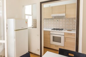 A compact kitchen with a refrigerator, stove, oven, and patterned backsplash.