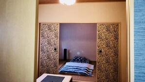 A small, cozy room with a bed, a ceiling fan, and a laptop on the floor.