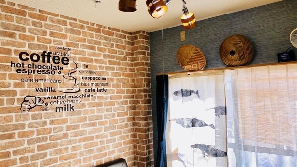 A cozy room with a brick wall, a coffee-themed wall art, a leather sofa, and a window with a view of fish.