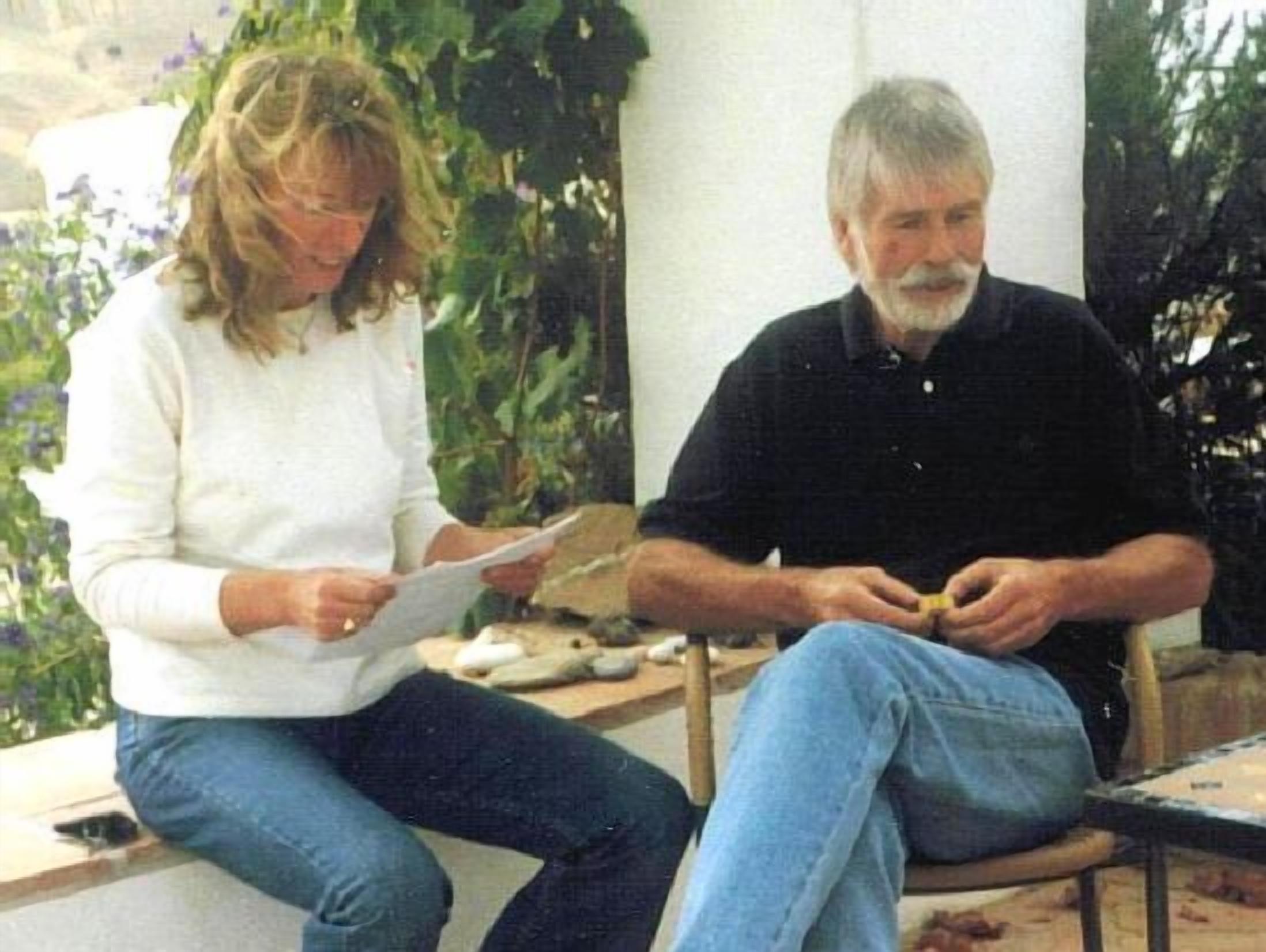 Deux personnes sont assises sur un banc à l’extérieur, et l’une d’elles tient des papiers.