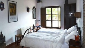 A bedroom with a bed, a window with a view, a radiator, and a framed picture on the wall. - Holiday home in a traditional finca in the heart of Andalusia (Antequera)
