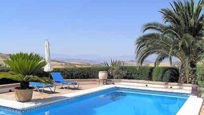 A swimming pool with a clear view of the surrounding landscape, including palm trees and a distant mountain range. - Holiday home in a traditional finca in the heart of Andalusia (Antequera)
