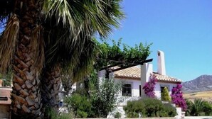 A white building with a tiled roof, surrounded by greenery and a mountain in the background. - Holiday home in a traditional finca in the heart of Andalusia (Antequera)