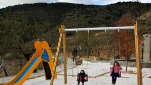 A playground with swings and a slide in a snowy setting.