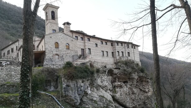 Un edificio in pietra con un campanile, situato a picco su una scogliera e con vista sul paesaggio circostante.