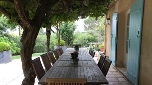 A long wooden table with chairs, a potted plant, and a blue door in the background. - A charming, 6-bedroom house in a convenient location (Gassin)