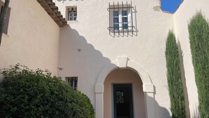 A building with a white facade, a tiled roof, and a small window with barred glass. - A charming, 6-bedroom house in a convenient location (Gassin)