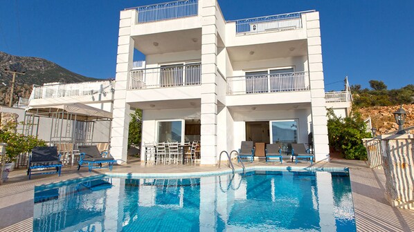 Et hotel med flere etager, en swimmingpool, udendørs siddepladser og altaner.