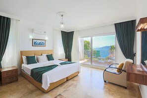 Et hotelværelse med seng, skrivebord, stol, balkon med udsigt og et klimaanlæg.