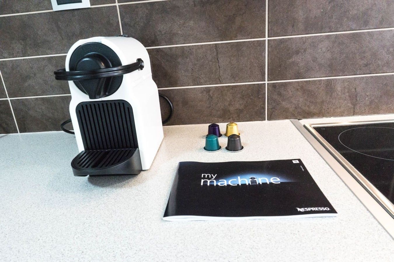 Una cucina con una macchina da caffè, un libretto intitolato 'my machine' e un piano cottura.