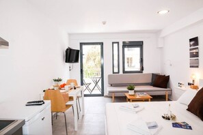 A compact living space with a kitchenette, a dining area, a sofa, and a bed.