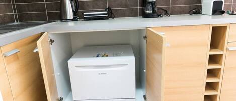 A kitchen with a built-in coffee maker, a kettle, and a toaster on the countertop.