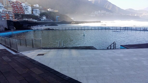 Ein Pool am Wasser mit Blick auf den Ozean und ein bergiges Hinterland.