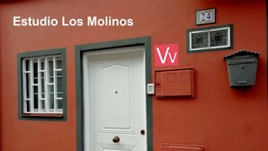 Eine weiße Tür mit kleinem Fenster darüber, einem Briefkasten und einer an der Wand befestigten Hausnummer.