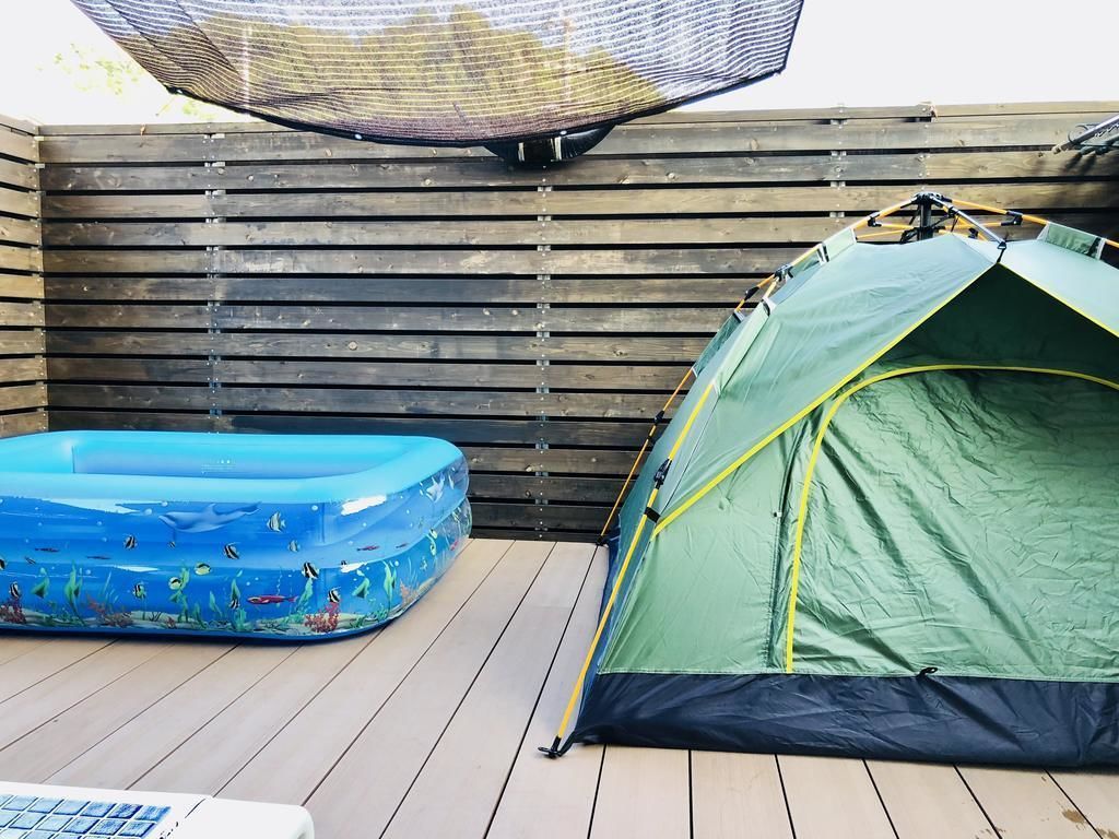 Una tienda de campaña y una piscina inflable sobre una terraza de madera.