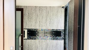 Une salle de bain moderne avec un mur en bois, un lavabo noir et un pare-feu en carreaux.