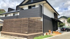 Une maison moderne à deux étages, avec une façade sombre, un toit en pente et un garage apparent.