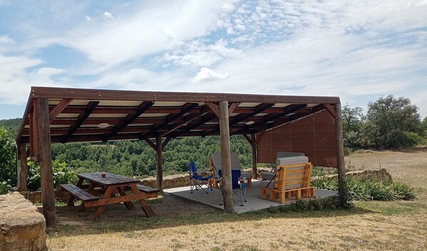 Un pavillon en bois avec une table de pique-nique et des chaises pliantes.