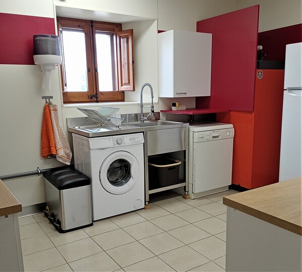 A compact kitchen with a washing machine, a sink, and a refrigerator.