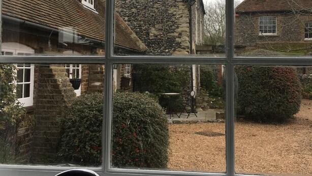 A window with a view of a stone building and a garden. - Well Cottage, a one bedroom self-catering holiday cottage all on one level. (Kent)