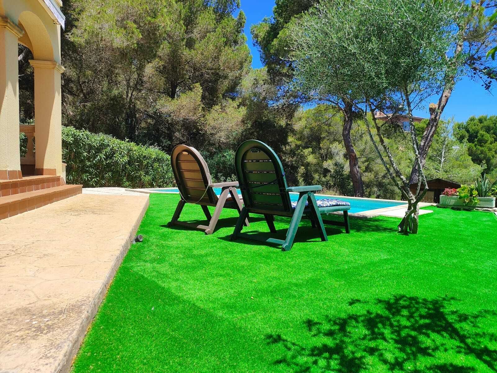 A poolside area with two lounge chairs, a small table, and a well-maintained lawn.