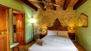 A bedroom with a stone wall, a wooden bed frame, two bedside lamps, and a wooden chair. - Self catering Can Nentia for 9 people (Forallac)