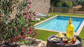 A poolside area with a stone wall, a small garden with pink flowers, and a table with snacks and drinks. - Self catering Can Nentia for 9 people (Forallac)