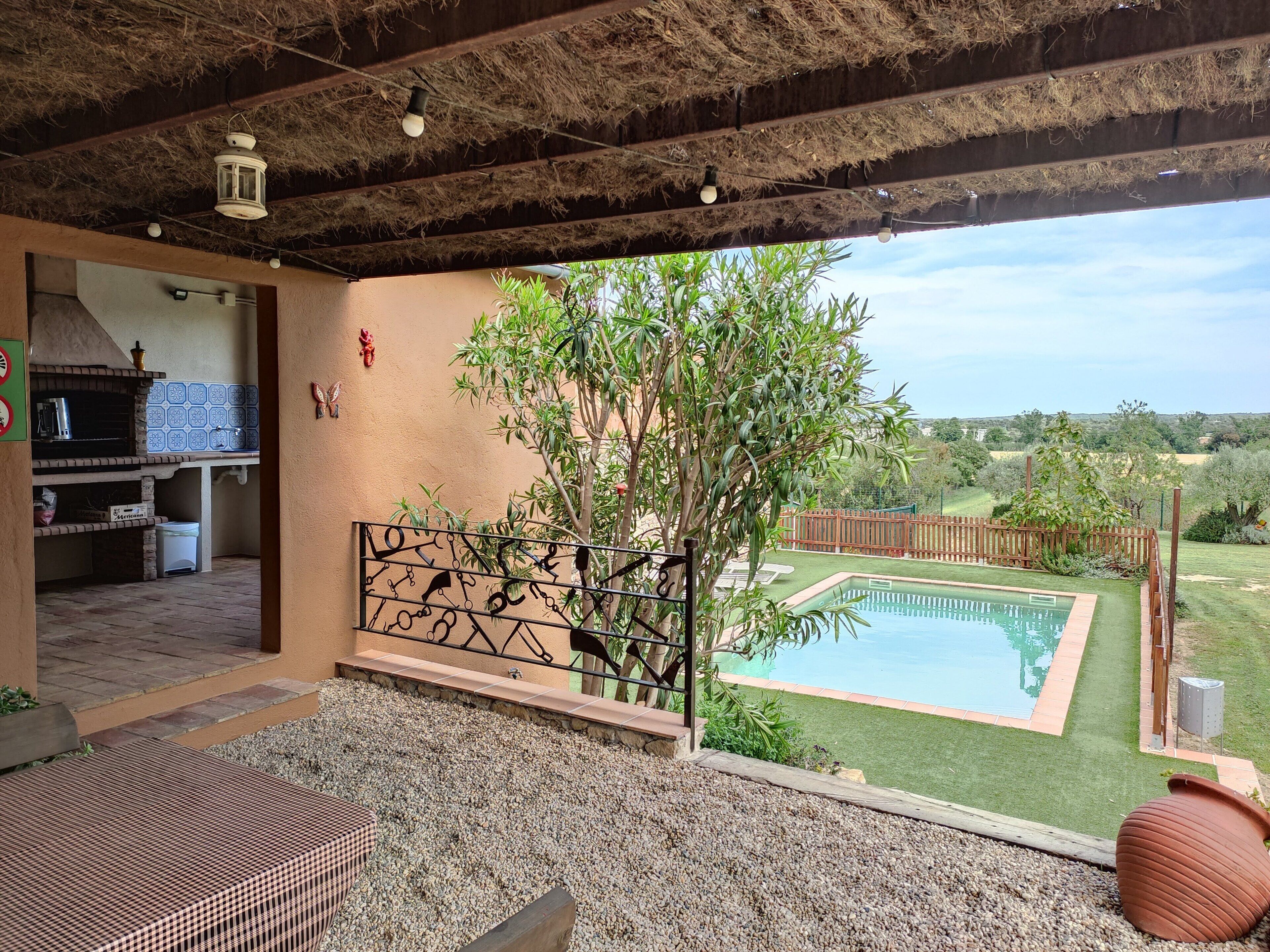 Une terrasse extérieure avec une piscine, un barbecue et une vue sur le paysage environnant.