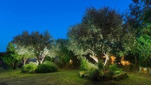 A garden at dusk with trees and shrubs, illuminated by soft lighting. - Self catering Can Nentia for 9 people (Forallac)