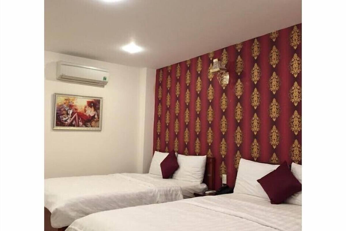A hotel room with two beds, a painting on the wall, and a patterned wallpaper.