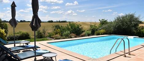 Een buitenzwembad, ligstoelen bij het zwembad