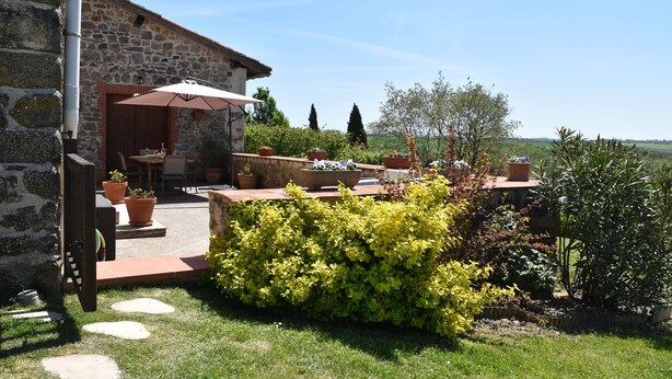 Un bâtiment en pierre doté d’un patio, d’un espace extérieur aménagé avec des sièges et de plantes en pot.