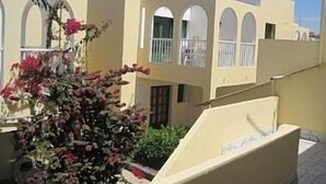 Un edificio con finestre ad arco e balconi, immerso nel verde e fiorito.