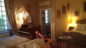 Un dormitorio acogedor con una cama, una silla, una mesita y un aparador.