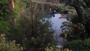 Un paysage montagneux avec une étendue d’eau, des arbres et un petit bâtiment.