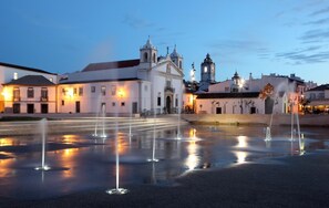 A historic plaza with fountains, a church, and traditional buildings.