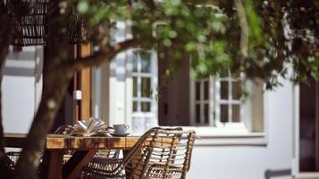A wooden table with wicker chairs, a book, and a teacup.