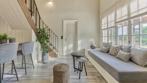 A spacious living area with a wooden staircase, a sofa set, and a dining table. - Classic Three Bedroom Cottage with private pool (Zakynthos)