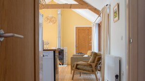 Un espace de vie chaleureux et ouvert, avec un plancher en bois, un coin repas et une cuisine équipée d’une cuisinière intégrée.