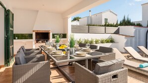 An outdoor dining area with wicker furniture, a long table, and a grill. - Villa La Calma - beach,private Pool, free AC&WiFi (Es Mercadal)
