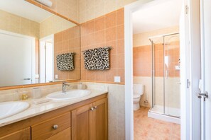 A bathroom with two sinks, a mirror, a shower, and a leopard print towel.