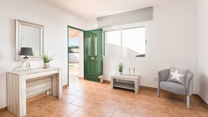 A spacious room with a wooden console table, a green door, a window, and a grey armchair. - Villa La Calma - beach,private Pool, free AC&WiFi (Es Mercadal)