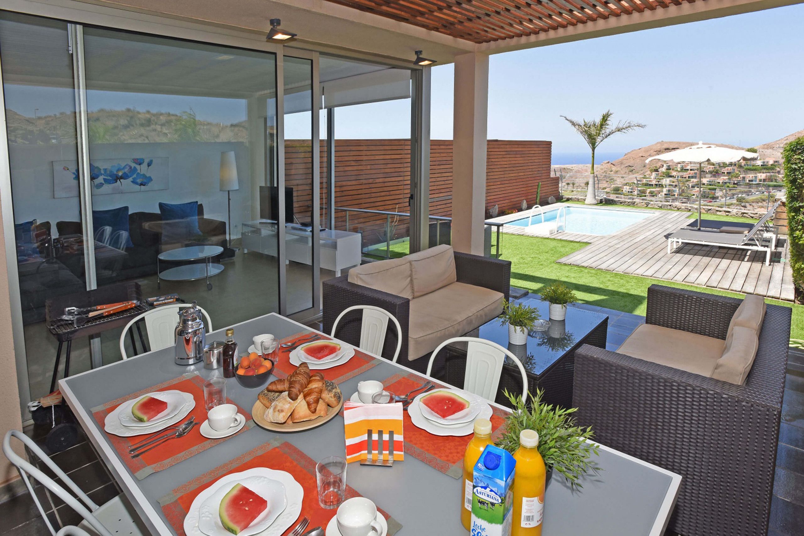 A modern outdoor dining area with a view of the pool and hills.