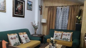 Una sala acogedora con un sofá verde, cojines amarillos y una mesa de centro de madera.