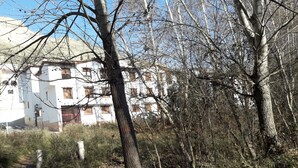 Un edificio con varias ventanas y balcones, rodeado de árboles y un sendero de tierra.